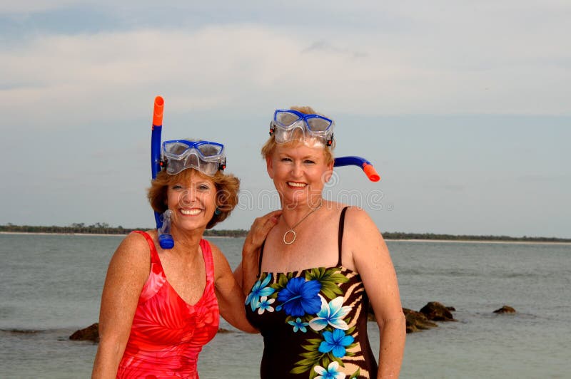 Dos mujer en nadar trajes a tubo respirador equipo sobre el Playa.