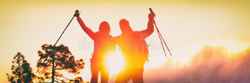 Active outdoor lifestyle couple hikers cheering success achieving their adventure goal trekking mountain top with hiking poles.