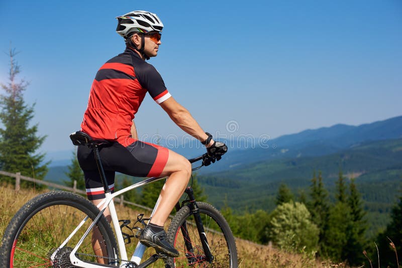 Active professional sportsman cyclist stopped bicycle on top of hill