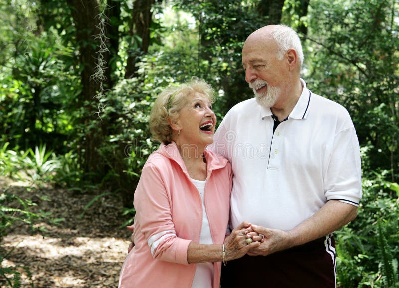 Un felice e attiva coppia senior a ridere insieme in una passeggiata attraverso il parco.