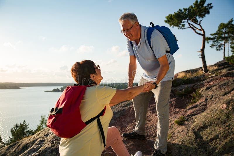 Active senior couple hiking on the top of rock