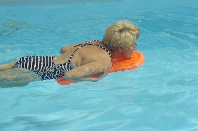 Activo una mujer mientras Agua gimnasia en cálido piscina pequeno lámina en su manos.