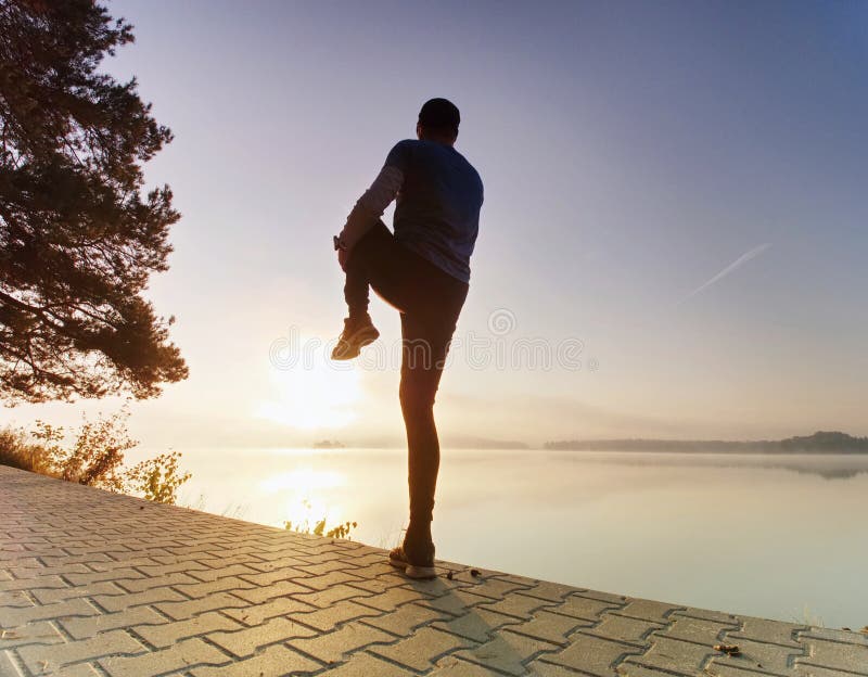 Active sport man runner stretching body on pavement lake side stock images Active sport man runner stretching body on pavement lake side stock images