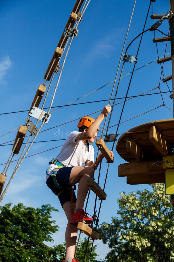 Active sporty kid in helmet doing activity in adventure park with all climbing equipment. Active children climb on the trees stock image Active sporty kid in helmet doing activity in adventure park with all climbing equipment. Active children climb on the trees stock image