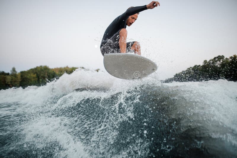 Active wakeboarder jumping on the blue splashing wave against th stock image