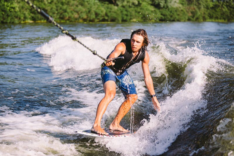 Active Wakesurfer Jumping on Wake Board Down the River Waves. Surfer on