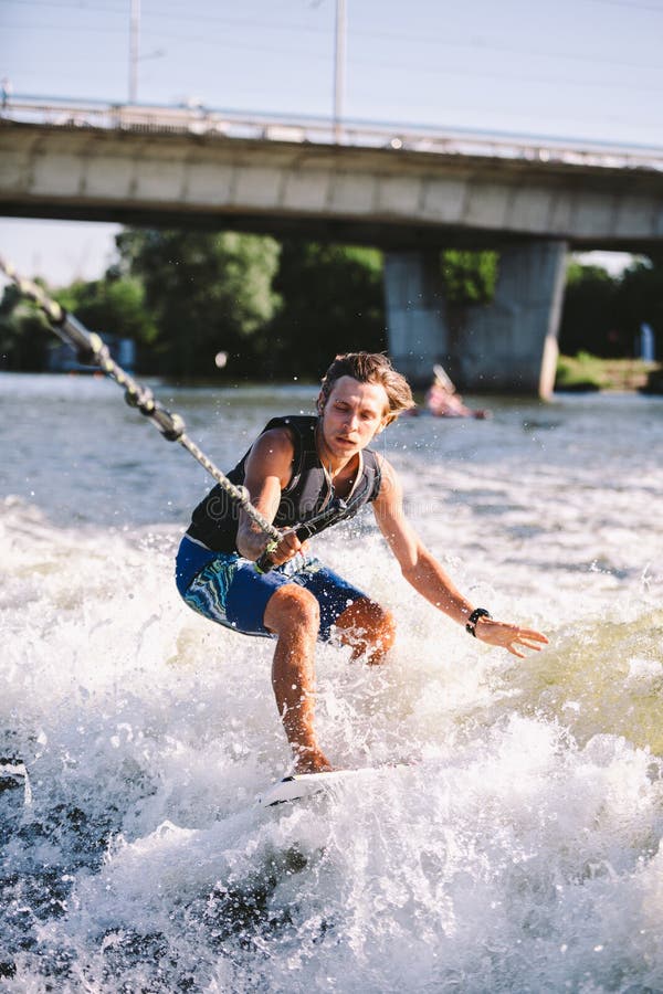 Active Wakesurfer Jumping on Wake Board Down the River Waves. Surfer on