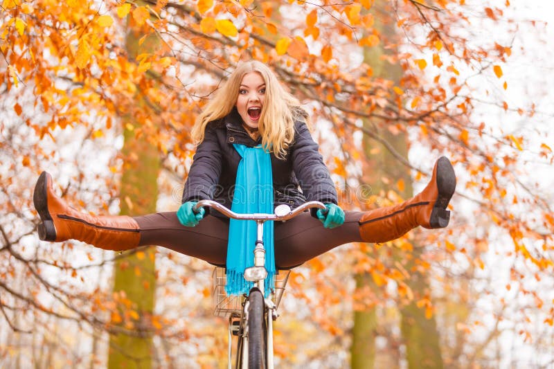 Active woman having fun riding bike in autumn park