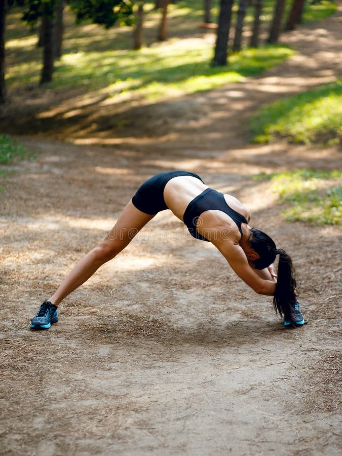 Active young woman workout outside, doing stretching exercises on legs and hands on the left side, on park background stock photo Active young woman workout outside, doing stretching exercises on legs and hands on the left side, on park background stock photo