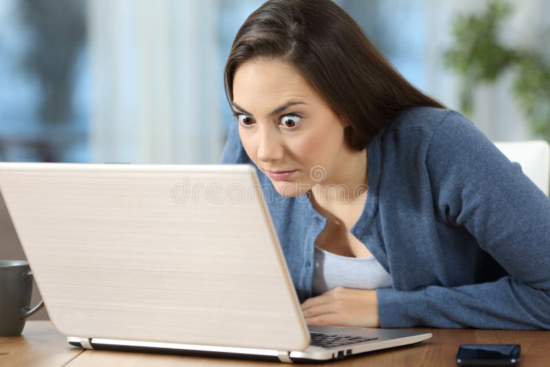 Actualités en ligne de lecture de femme perplexe dans un ordinateur portable photo stock Actualités en ligne de lecture de femme perplexe dans un ordinateur portable photo stock