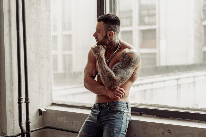 Adatti il ritratto del modello maschio nudo sexy con il tatuaggio e di una barba nera che sta nella posa calda sopra vicino alla fotografia stock libera da diritti Adatti il ritratto del modello maschio nudo sexy con il tatuaggio e di una barba nera che sta nella posa calda sopra vicino alla fotografia stock libera da diritti
