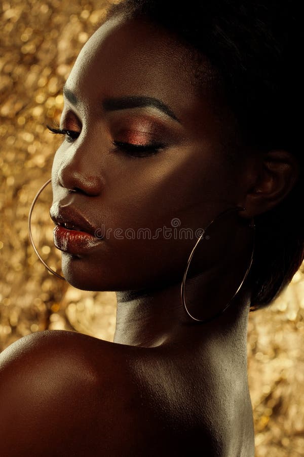 Adatti il ritratto dello studio di bello modello afroamericano straordinario con gli occhi chiusi sopra fondo dorato fotografia stock libera da diritti Adatti il ritratto dello studio di bello modello afroamericano straordinario con gli occhi chiusi sopra fondo dorato fotografia stock libera da diritti