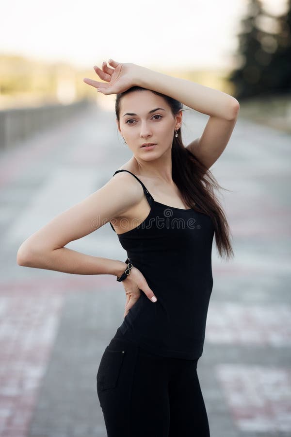 Adatti a ritratto di stile di vita la giovane donna graziosa castana che posa nella sera del tramonto dell'estate della banchina immagine stock Adatti a ritratto di stile di vita la giovane donna graziosa castana che posa nella sera del tramonto dell'estate della banchina immagine stock