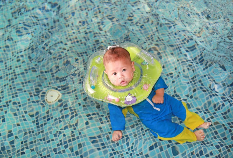 Addestramento infantile del neonato da nuotare in stagno con sicurezza dai galleggianti del collo del bambino fotografie stock Addestramento infantile del neonato da nuotare in stagno con sicurezza dai galleggianti del collo del bambino fotografie stock