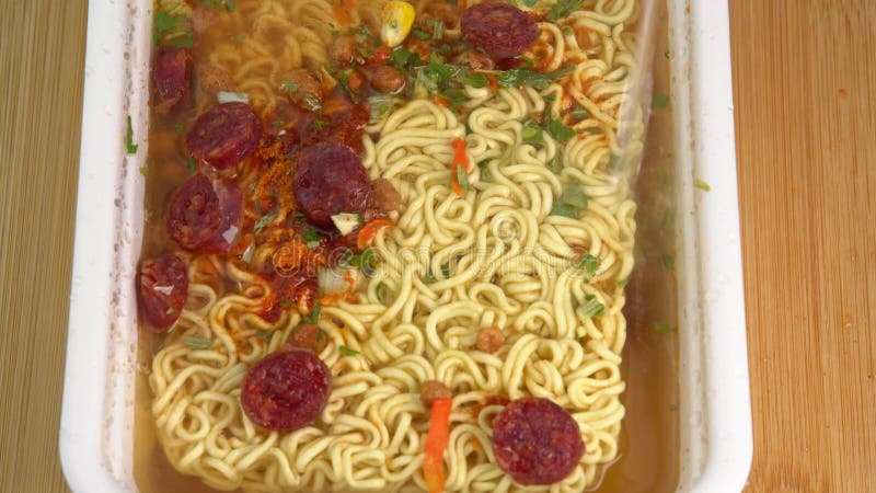 Adding Boiled Water To Instant Noodles in a Bowl Rotate on Wooden