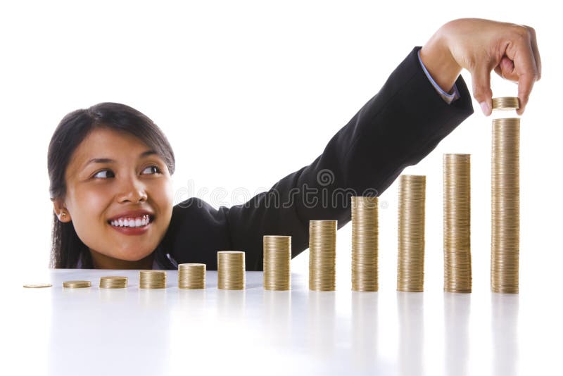 A young Asian businesswoman adding some coins to the highest stack in the most right row. Twelve stack represent twelve months in a year.Main focus on coin stacks. A young Asian businesswoman adding some coins to the highest stack in the most right row. Twelve stack represent twelve months in a year.Main focus on coin stacks.