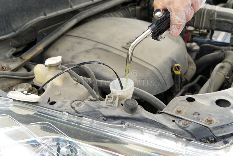 Adding Windshield Washer Fluid at Gasolin Station by Driver. Closeup