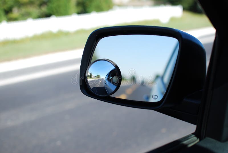 The addition of a convex mirror gives a view of a blind spot. A round convex mirror in focus attached to a vehicle`s side view mirror rest of image, out of focus. The convex mirror provides a wider field of view.