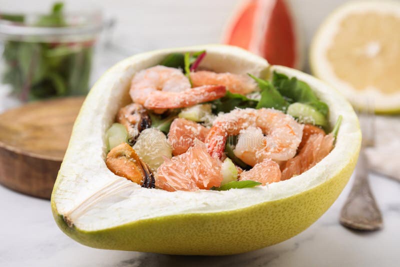Adekvat pomelosallad med räkor i hälften av frukt på bordsduken royaltyfri fotografi