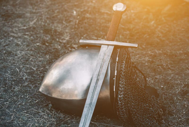 Adeln Sie ` s Sturzhelm und das glänzende Metall, das aus den Grund liegt, setzte er eine alte Stahlklinge mit ledernem Griff stockbild Adeln Sie ` s Sturzhelm und das glänzende Metall, das aus den Grund liegt, setzte er eine alte Stahlklinge mit ledernem Griff stockbild