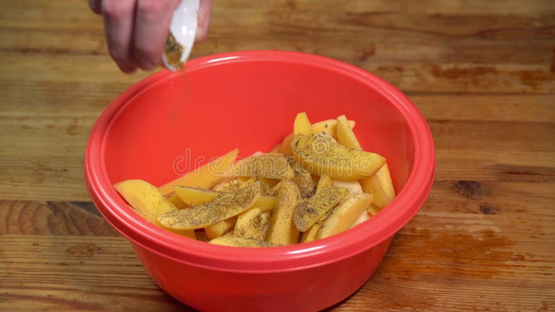 Adición de especias a las patatas en rodajas. una mano tiró patatas frescas en rodajas en un tazón. el cocinero está cortando papa almacen de metraje de vídeo