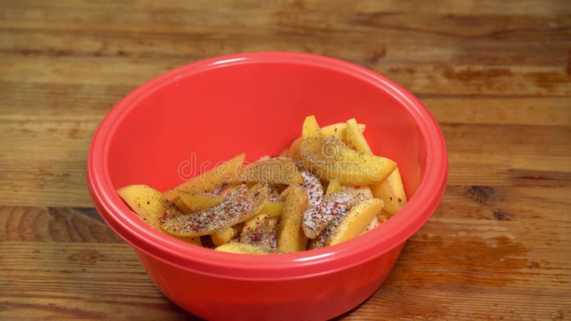 Adición de sal a las patatas en rodajas. una mano tiró patatas frescas en rodajas en un tazón. el cocinero está cortando papa en m metrajes