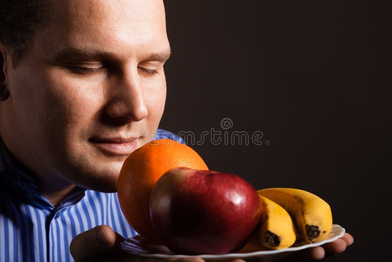Adiete la nutrición Frutas que huelen felices del hombre joven imágenes de archivo libres de regalías Adiete la nutrición Frutas que huelen felices del hombre joven imágenes de archivo libres de regalías
