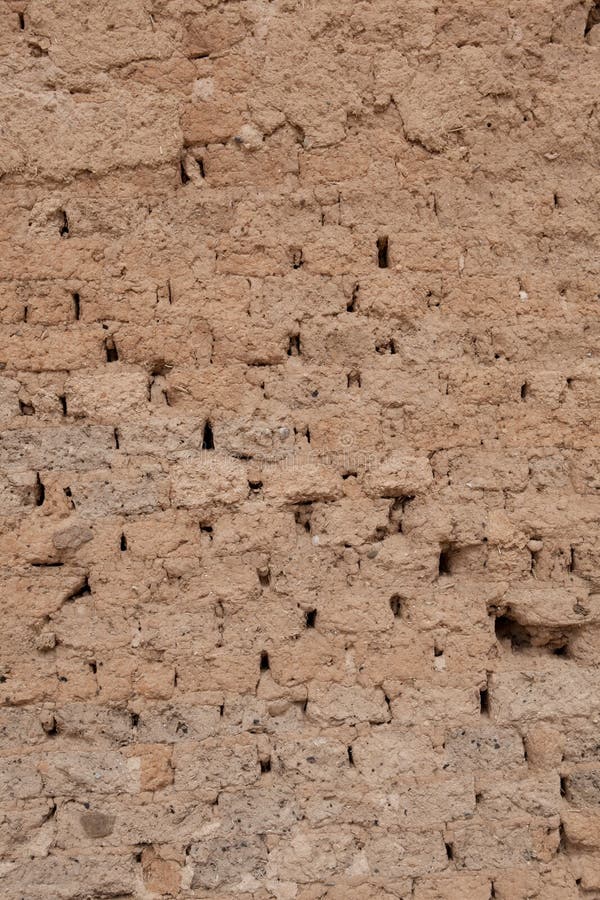 Adobe brick wall with worn-off plaster