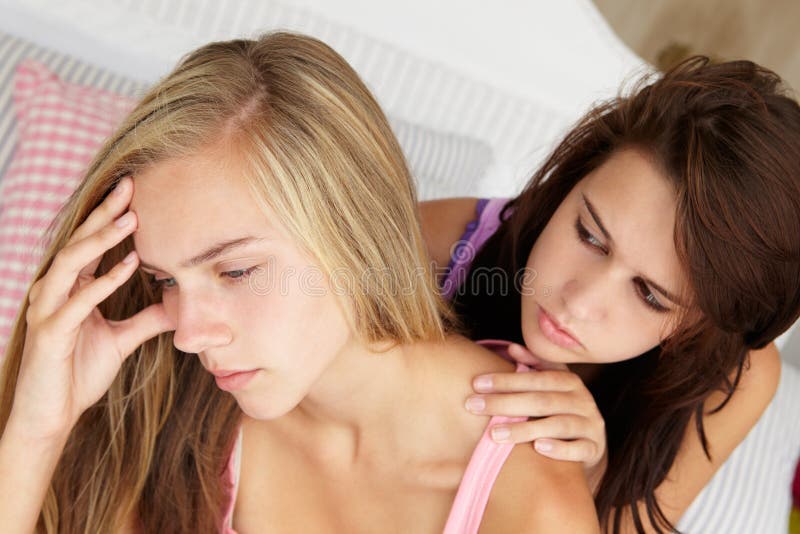 Upset teenager being comforted by friend in bedroom. Upset teenager being comforted by friend in bedroom