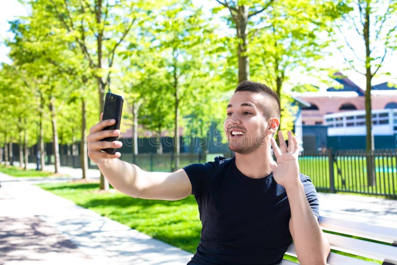 Adolescent de sourire parlant par l'intermédiaire de la caméra de téléphone portable pendant la récréation images stock Adolescent de sourire parlant par l'intermédiaire de la caméra de téléphone portable pendant la récréation images stock