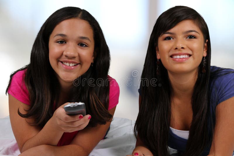 Teenage girl laying in her bed with her friend watching TV. Teenage girl laying in her bed with her friend watching TV
