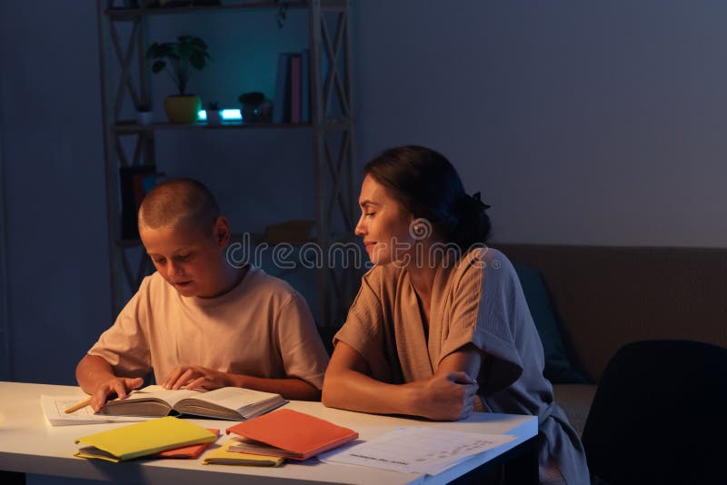 Adolescenta baiat este atent face temele sale fiu citind o carte mama sta langa fiu si uita cu zambet. Concept și educație stock photo