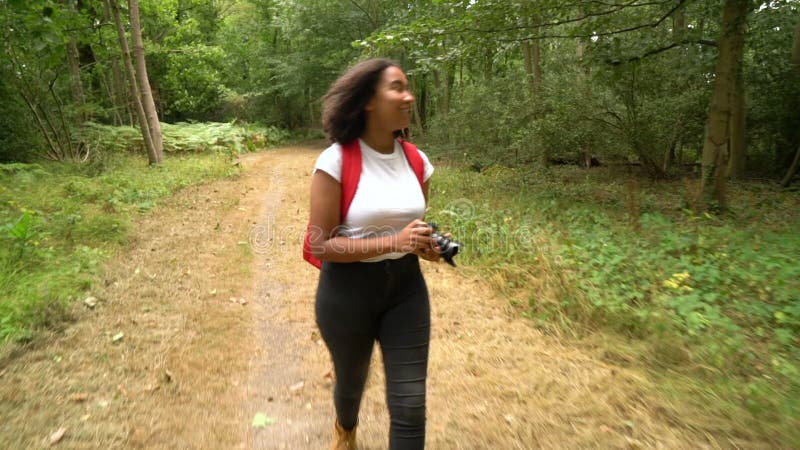 Adolescente africaine américaine mixte race fille jeune femme prenant des photos avec un appareil photo dans forêt boisé banque de vidéos