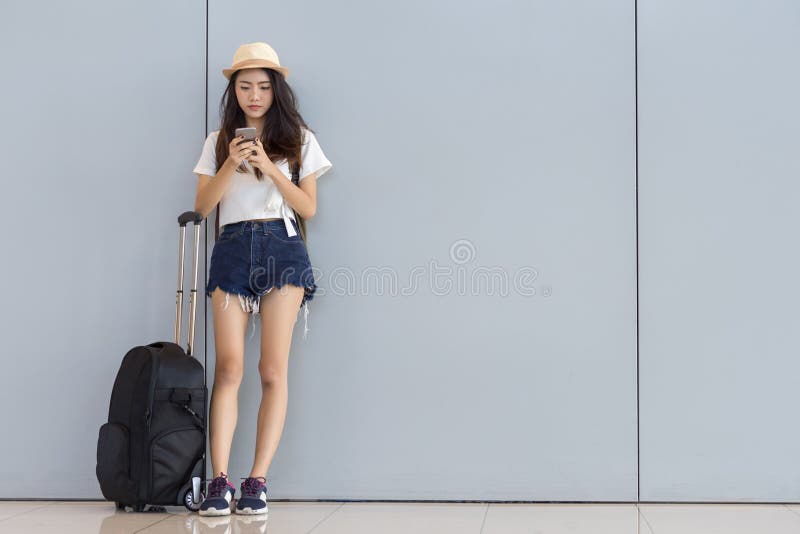 Adolescente asiático da mulher que usa o smartphone no aeroporto foto de stock Adolescente asiático da mulher que usa o smartphone no aeroporto foto de stock