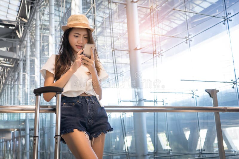 Adolescente asiático de la mujer que usa smartphone en el aeropuerto imagen de archivo libre de regalías Adolescente asiático de la mujer que usa smartphone en el aeropuerto imagen de archivo libre de regalías