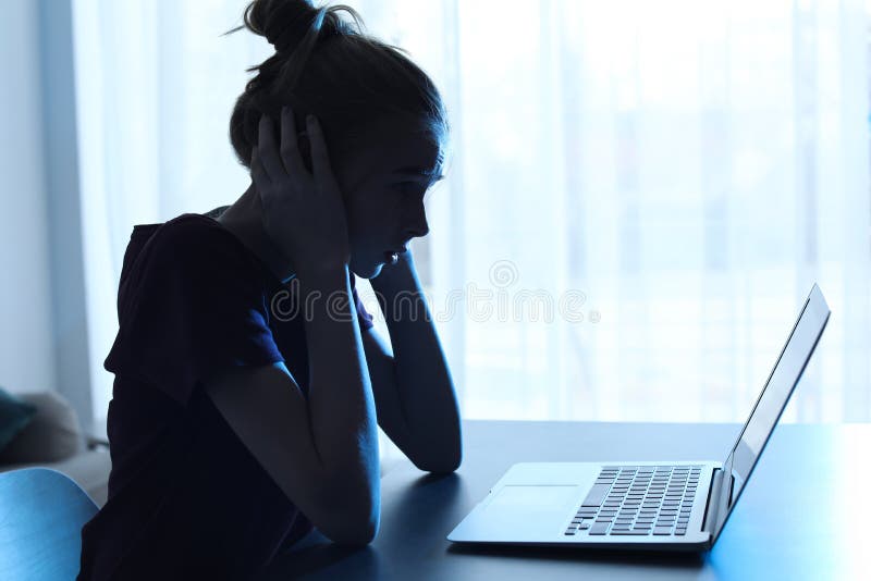 Adolescente aterrorizado con el ordenador portátil en la tabla Peligro de Internet