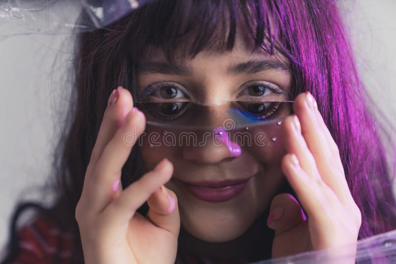 White teenage girl with purple hair looking into camera holding broken CD under her eyes. Creative portrait photography. Horizontal shot. High quality photo. White teenage girl with purple hair looking into camera holding broken CD under her eyes. Creative portrait photography. Horizontal shot. High quality photo