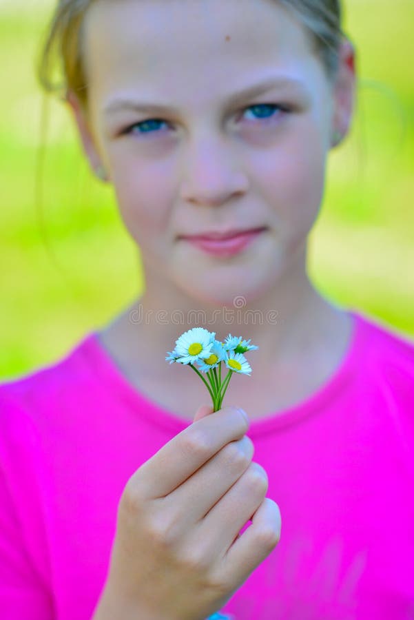 Adolescente bonito de sorriso com o ramalhete pequeno das margaridas imagem de stock royalty free Adolescente bonito de sorriso com o ramalhete pequeno das margaridas imagem de stock royalty free