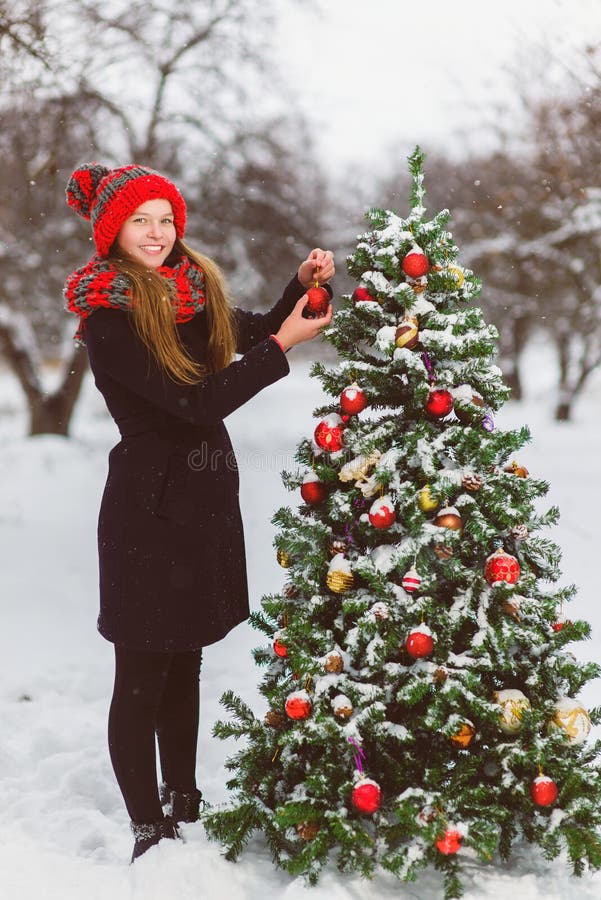 Cute teenager or girl decorating christmas tree outdoor. Cute teenager or girl decorating christmas tree outdoor.