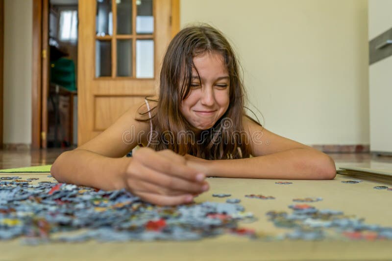 Adolescente brunette che fa un puzzle steso sul pavimento di casa sua passa del tempo scappando dalla tecnologia e fotografie stock libere da diritti