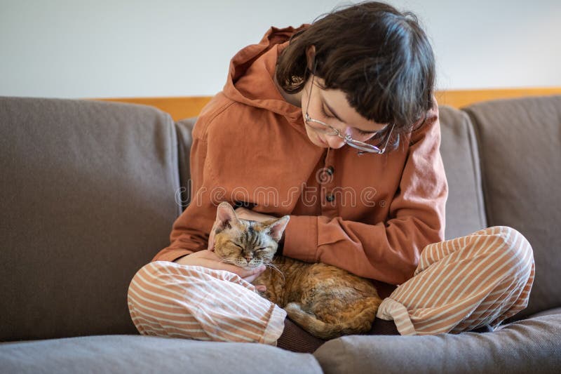 Adolescente caresser chat de l'abri assis sur le canapé à la maison. amoureux de chat image stock