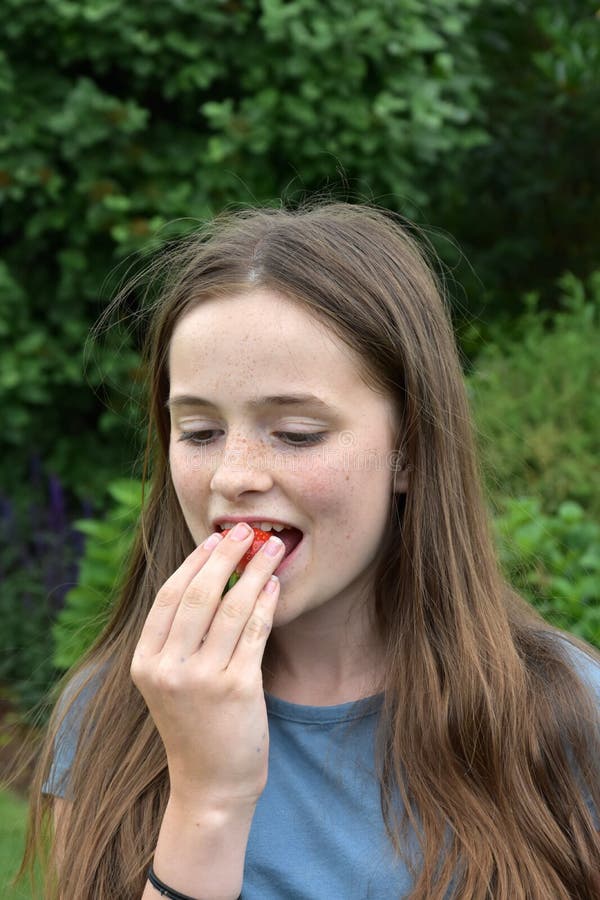 Adolescente che mangia una fragola immagine stock Adolescente che mangia una fragola immagine stock