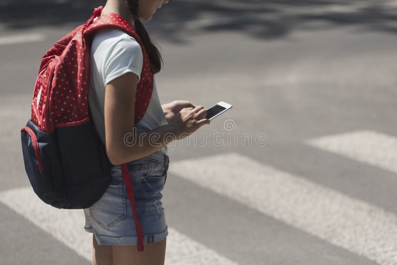 Adolescente con la mochila usando el teléfono durante su manera de la escuela fotografía de archivo libre de regalías Adolescente con la mochila usando el teléfono durante su manera de la escuela fotografía de archivo libre de regalías