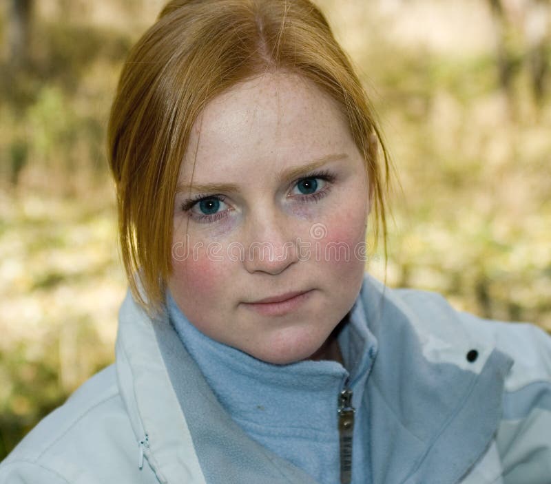 Young woman outdoors in cool weather with rosy cheeks and tired eyes. Young woman outdoors in cool weather with rosy cheeks and tired eyes.