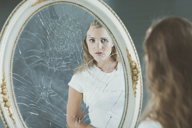 Pretty teenage girl with personality problems looking at herself in the mirror. Pretty teenage girl with personality problems looking at herself in the mirror