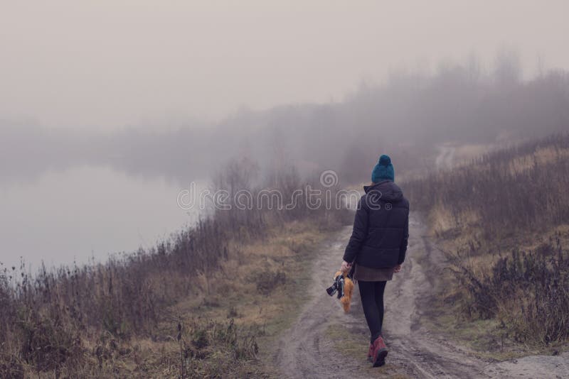 adolescente con un orsacchiotto su una strada di campagna al lago nebbioso Concetto di adolescenza e problemi dell'adolescenza immagine stock libera da diritti adolescente con un orsacchiotto su una strada di campagna al lago nebbioso Concetto di adolescenza e problemi dell'adolescenza immagine stock libera da diritti