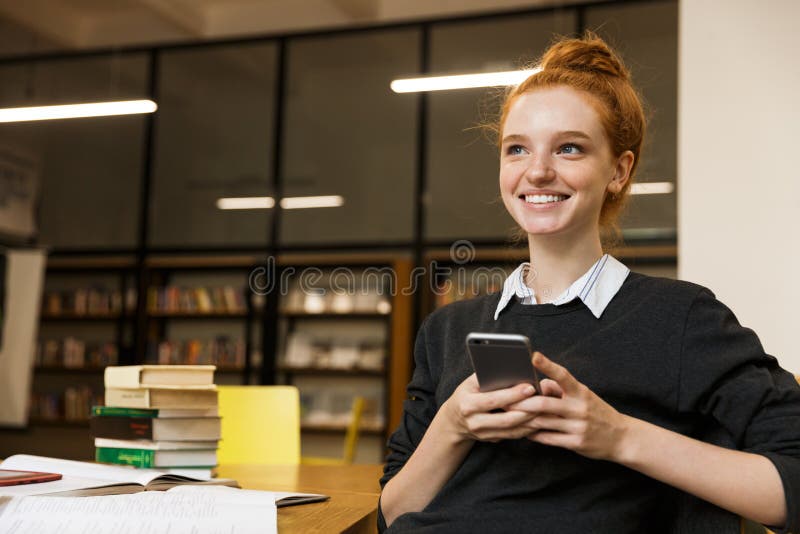 Adolescente dai capelli rossi felice che studia alla tavola fotografie stock libere da diritti Adolescente dai capelli rossi felice che studia alla tavola fotografie stock libere da diritti