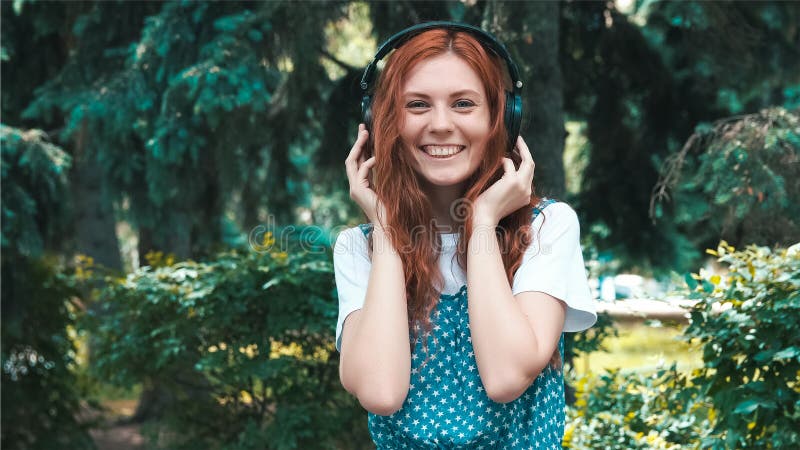 Adolescente dai capelli rossi Freckled ascoltare musica in grandi cuffie immagini stock libere da diritti Adolescente dai capelli rossi Freckled ascoltare musica in grandi cuffie immagini stock libere da diritti