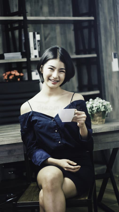 Adolescente de portrait dans la robe bleue luxueuse, souriant heureusement avec le regard lumineux, tenant la tasse de café blanc images stock