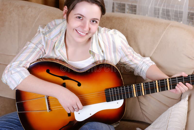 Adolescente de sorriso que joga pela guitarra fotografia de stock Adolescente de sorriso que joga pela guitarra fotografia de stock